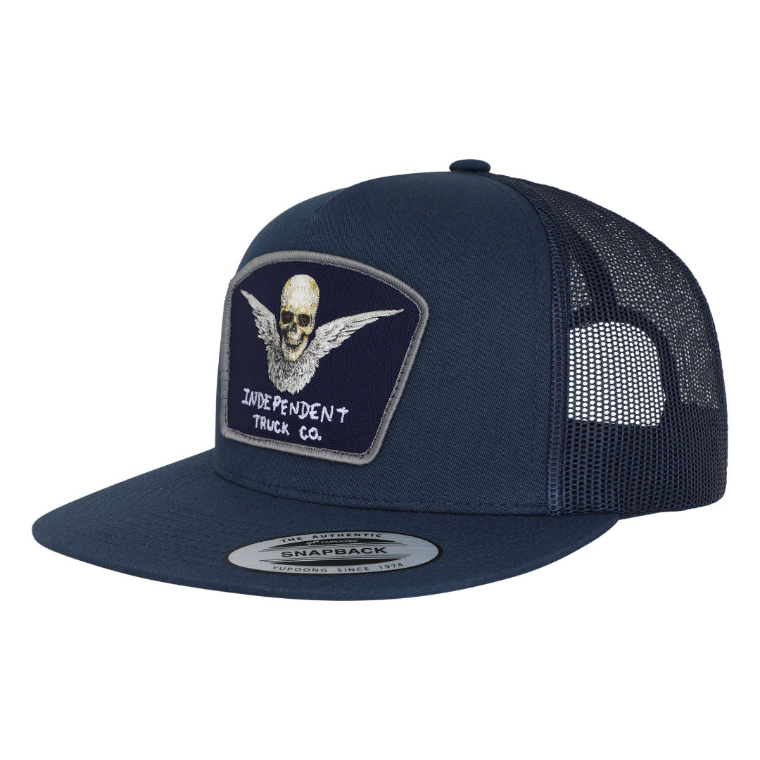 A navy blue trucker hat with a structured front panel, mesh back, and a patch on the front featuring a skull with wings and the text 'INDEPENDENT TRUCK CO.' A silver sticker is visible on the brim.