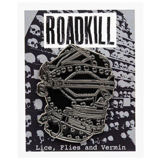 Metallic skull pin with 'Roadkill' branding on a black and white patterned background