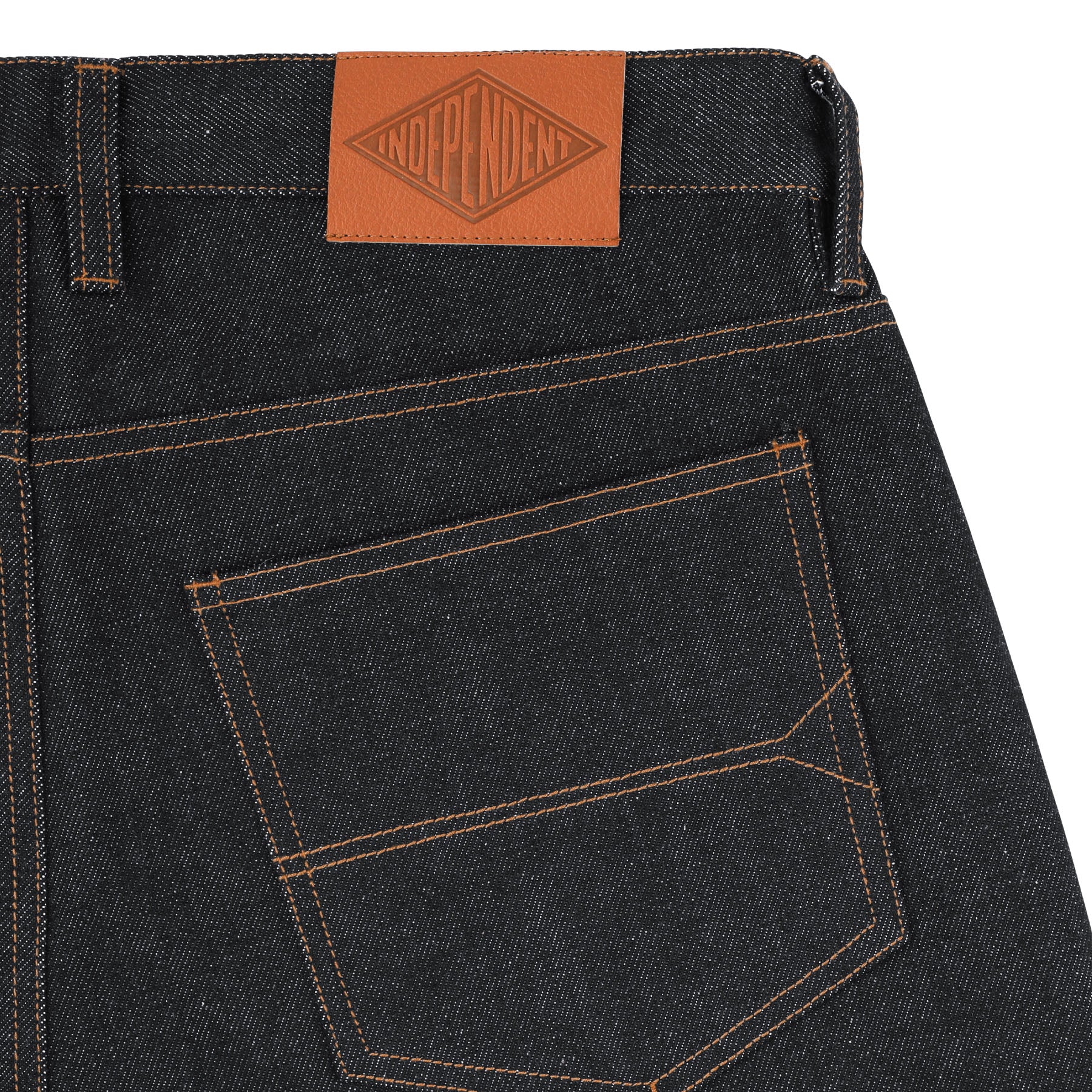 Close-up of black denim jeans with a brown leather patch and brand logo on a white background.