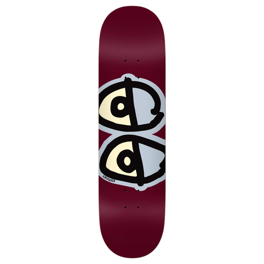 A skateboard deck with a deep burgundy background, featuring a graphic of two stylized eyes stacked vertically. The eyes are cream-colored with black outlines and a light gray shadow effect.