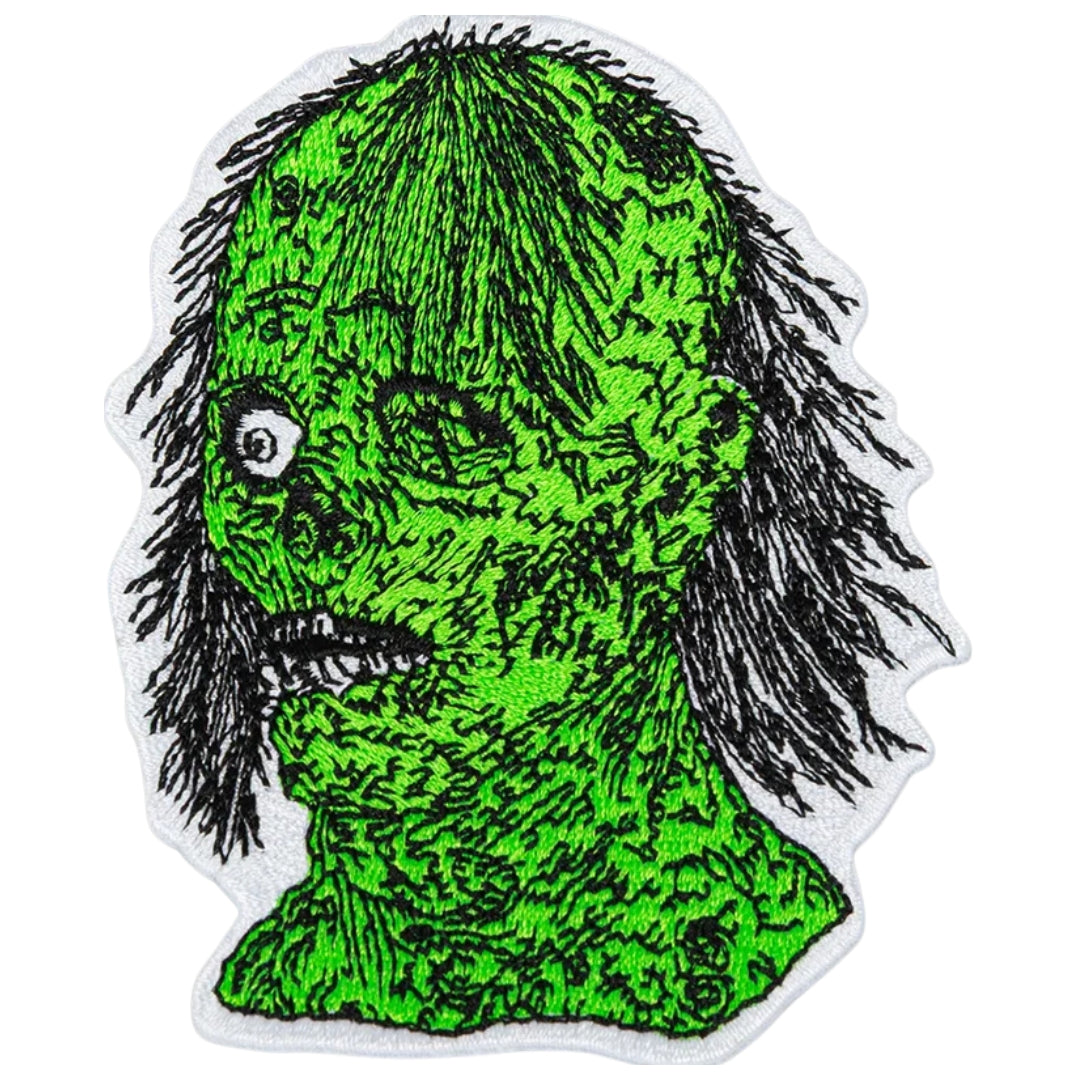 Green creature patch with black hair on a white background