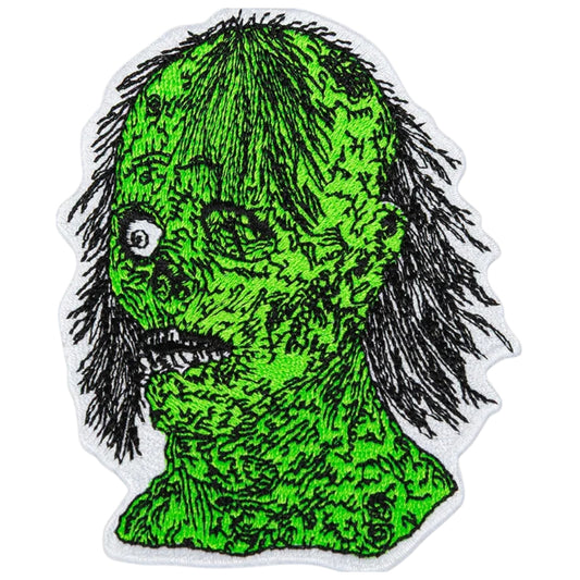 Green creature patch with black hair on a white background