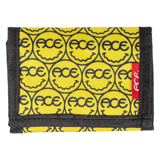 A yellow fabric wallet with a repeating black smiley face pattern containing the brand name 'FACE' and a red side tab with 'ACE' in white text, shown on a plain white background.